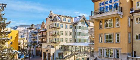 Ein historischer Stadtplatz mit einem markanten Glockenturm, einer überdachten Brücke und traditioneller europäischer Architektur.