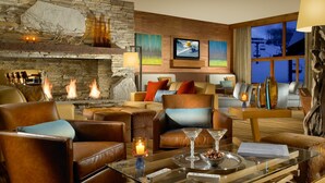 A cozy living room with a stone fireplace, comfortable seating, and a television mounted on the wall.