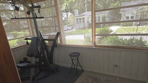 Une salle de sport à domicile équipée d’un vélo d’exercice, d’un banc et d’un petit tabouret.