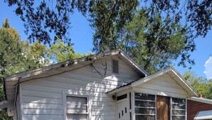 Une maison de plain-pied avec un porche à l’avant, un petit jardin et un ciel dégagé.