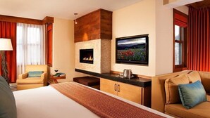 Ein Hotelzimmer mit einem großen Bett, einem Kamin, einem Fernseher und einem Sofa.