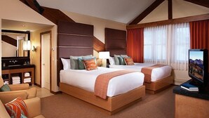 Hotelkamer met twee bedden, een bank, een televisie en een badkamer met spiegel en wastafel.