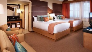 Een hotelkamer met twee bedden, een slaapbank, een bureau en een televisie.