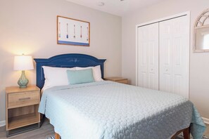 Ein Schlafzimmer mit Bett, Nachttisch, Lampe und einer Tür.