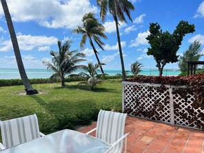 Relax in a serene ocean-view patio with comfortable wicker furniture and lush greenery.