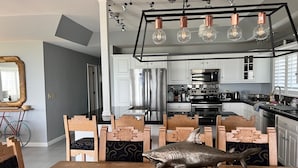A modern kitchen with white cabinets, stainless steel appliances, and a dining area with a shark sculpture centerpiece.