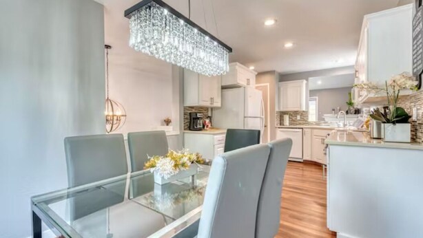 A modern kitchen with white cabinets, a central island, and a chandelier. - Tranquil Urban Oasis in Bonney Lake (Bonney Lake)