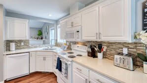 A modern kitchen with white cabinetry, a granite countertop, and a stainless steel range hood. - Tranquil Urban Oasis in Bonney Lake (Bonney Lake)