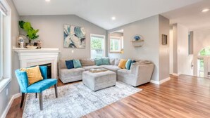 A spacious living room with a sectional sofa, a blue armchair, and a fireplace. - Tranquil Urban Oasis in Bonney Lake (Bonney Lake)