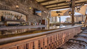 A bar with a stone wall, wooden bar counter, and hanging lights.