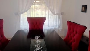 Ein Konferenzraum mit einem schwarzen Tisch, roten Polsterstühlen, weißen Vorhängen und einem Fenster mit Jalousien.