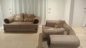 Ein Wohnzimmer mit zwei Sofas, eines mit Blumenmuster und das andere einfarbig, beide mit passenden Kissen.