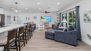 Ein modernes Wohnzimmer mit einer Couch, Sesseln, einem Couchtisch und einem Fernseher.