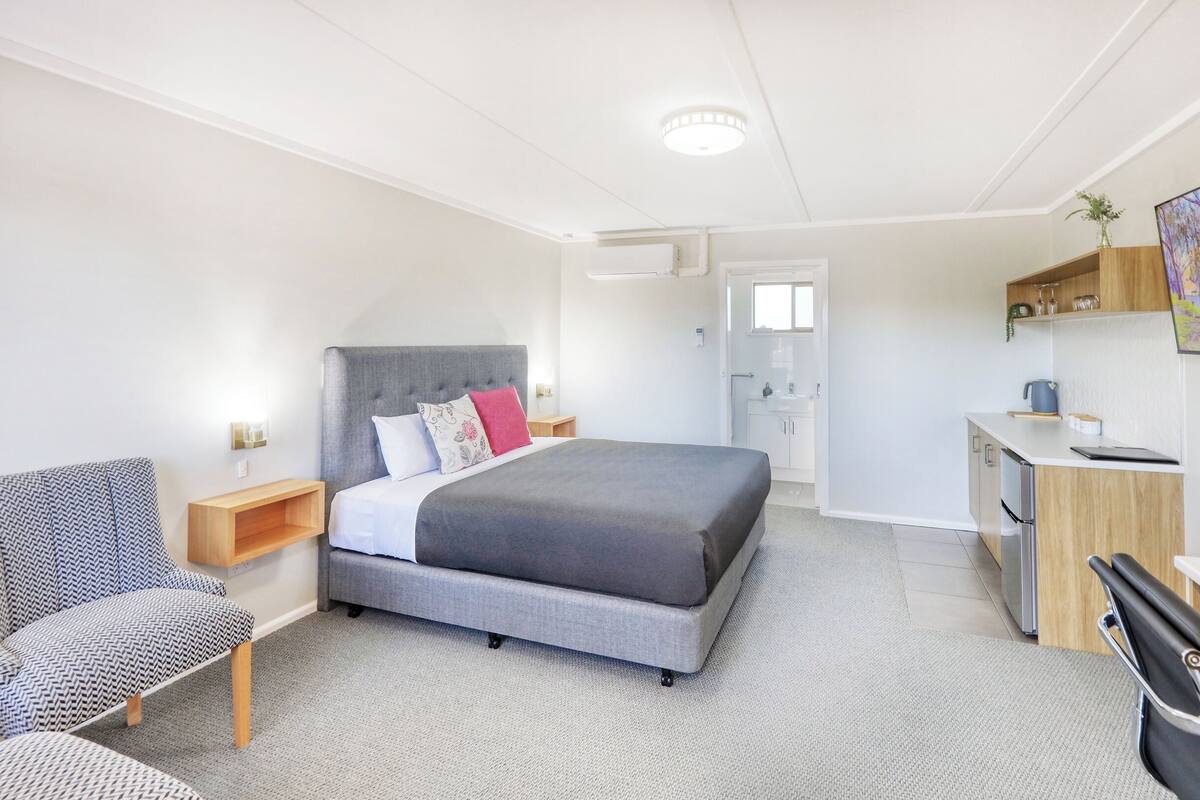 Una habitación de hotel moderna con cama, escritorio, silla y televisión.