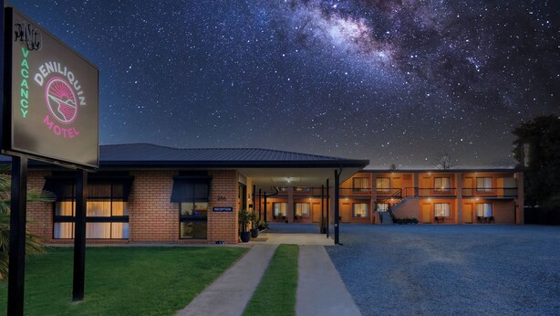 A motel with a reception area, a covered parking lot, and a starry night sky.
