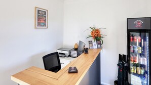 A reception desk with a framed poster, a computer, a printer, and a vase of flowers.