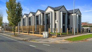 A row of modern, single-story houses with a uniform design, featuring large windows and a flat roof. - Norton Motel (Hamilton)