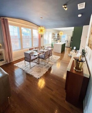 A dining area with a table set for four, a kitchen in the background, and a bar area with a bottle of champagne.