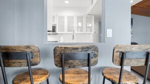 Three rustic chairs with metal frames and wooden seats, facing a modern kitchen with white cabinets and a stainless steel appliance. - Stylish Scottsdale Home W/ Pool Heating! (Scottsdale)