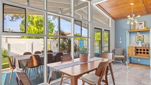 A spacious indoor area with a pool, dining area, and a kitchen. - Stylish Scottsdale Home W/ Pool Heating! (Scottsdale)