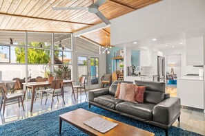 A modern living room with a leather sofa, a coffee table, and a dining area with chairs and a table.