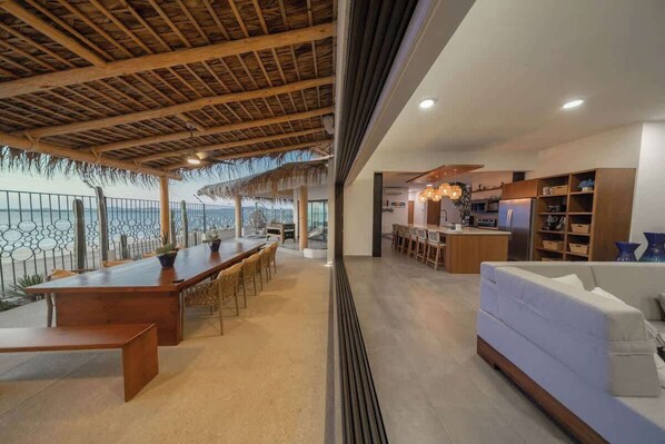 A modern kitchen with wooden cabinets and a dining area with a long table and chairs. - Beachfront Villa with Heated Pool (La Paz)