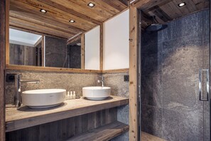 Un baño moderno con dos lavabos, un espejo grande y una zona de ducha.