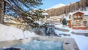 Un jacuzzi en un entorno nevado al aire libre, con montañas al fondo.