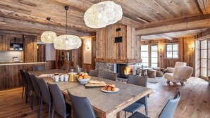 Interior rústico de madera con comedor, cocina y chimenea.