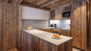 Una cocina con armarios de madera, encimera de granito, microondas, cafetera y tostadora.