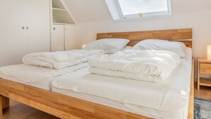 Makuuhuoneessa on puinen sänky, valkoiset vuodevaatteet, kattovalokuvio ja vaatekaappi.