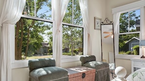 A room with two grey armchairs, a small table, a hutch with a lock, and a mirror on the wall. - Lovely Home- near fine dining and pool area (Bret Harte Cottage) (Angels Camp)
