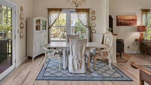 A dining room with a table and chairs, a chandelier, a window with curtains, and a fireplace. - Lovely Home- near fine dining and pool area (Bret Harte Cottage) (Angels Camp)