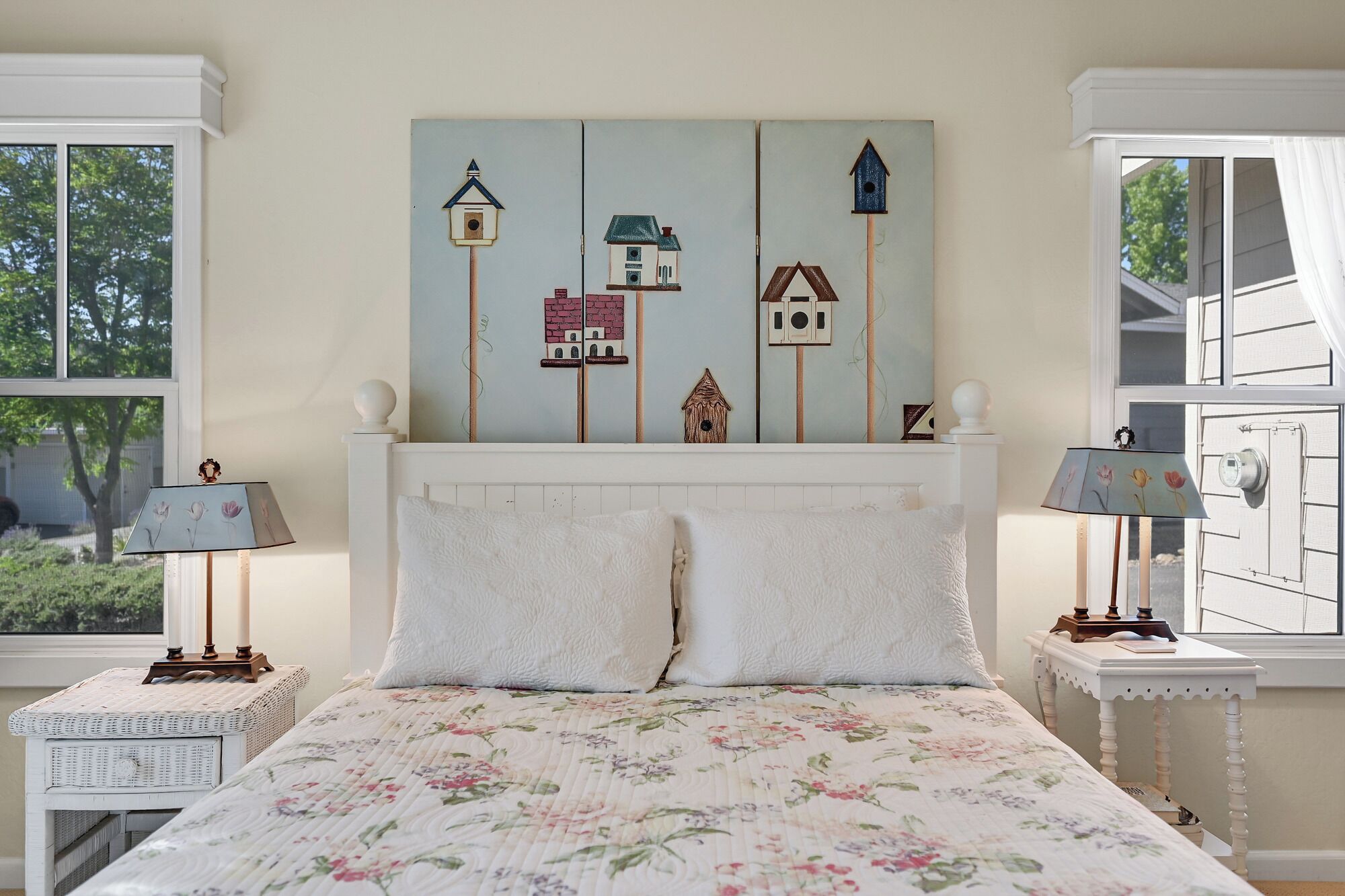 Une chambre à coucher comprenant un lit, deux tables de chevet, une tête de lit agrémentée d’une œuvre d’art murale et deux lampes.