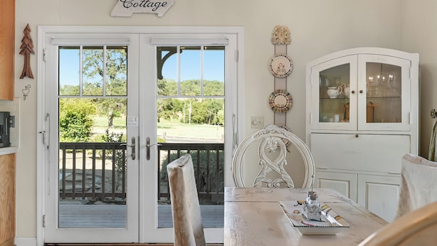 A dining area with a table, chairs, a white cabinet with glass doors, and a sign reading "Cottage" above the doors. - Lovely Home- near fine dining and pool area (Bret Harte Cottage) (Angels Camp)