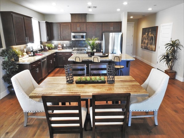 A modern kitchen with dark wood cabinets, stainless steel appliances, and a central island with seating.