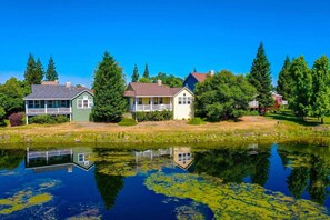 A lakeside property with multiple houses, a dock, and a reflection in the water.