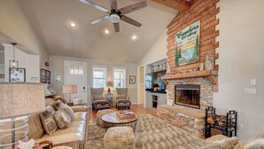 A cozy living room with a fireplace, leather sofas, and a stone accent wall. - Beautifully furnished home with HOT TUB (Angels Camp)