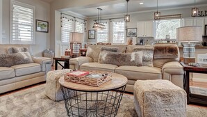 A spacious living room with a beige sofa, a round coffee table, and a fireplace. - Beautifully furnished home with HOT TUB (Angels Camp)