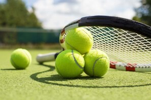 A tennis racket and three tennis balls on a green surface. - Raspberry Cottage-stunning view of golfcourse (Angels Camp)
