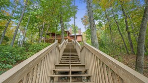 Una escalera de madera que lleva a una cabaña rodeada de árboles.