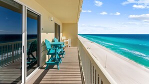 A balcony with a view of the ocean, a table with chairs, and a small table with a chair. - GULF FRONT BEDROOM @ CELADON BEACH RESORT ~FREE Beach Chair Service! (Panama City Beach)