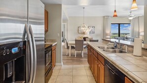 A modern kitchen with stainless steel appliances, a dining area with a chandelier, and a view of the city from the window.