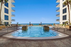 A pool area with two hot tubs, lounge chairs, and a view of the ocean. - Ocean Views, Pier Park, Origin at Seahaven 1703 (Panama City Beach)