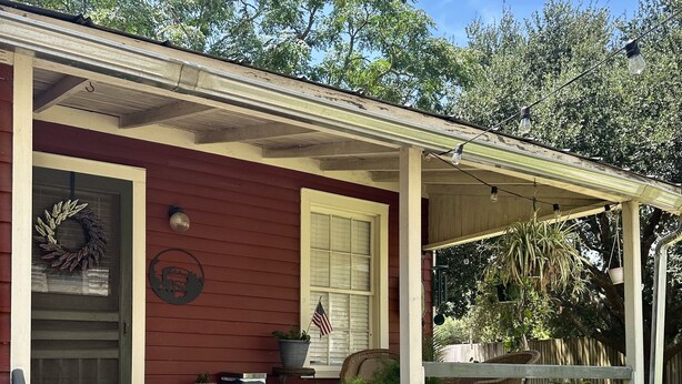 A red house with a porch, steps, a wreath, an American flag, and a potted plant. - Wensel Cottage in downtown Natchez Walking distance to most shops & restaurants. (Natchez)