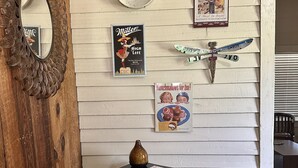 A room with a wooden floor, a black dresser, a mirror, and various vintage posters on the wall. - Wensel Cottage in downtown Natchez Walking distance to most shops & restaurants. (Natchez)