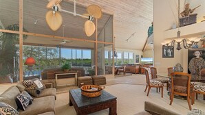 A spacious living area with a high ceiling, large windows, and a mix of modern and traditional furnishings.