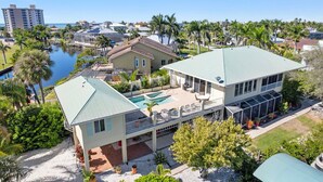 A large house with a pool, a covered patio, and a view of the ocean.