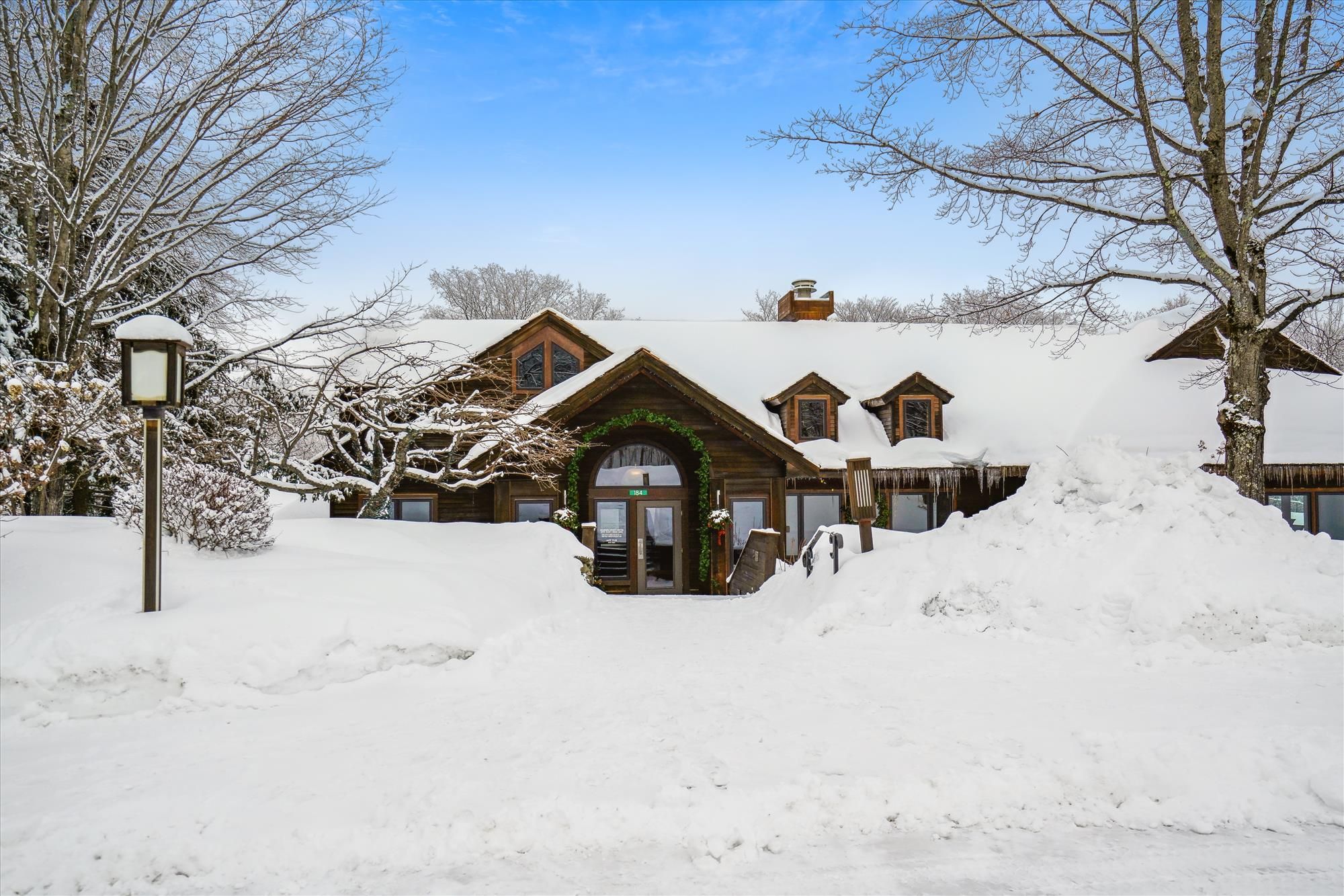 A snow-covered lodge with a prominent entrance and a large snow pile in front.