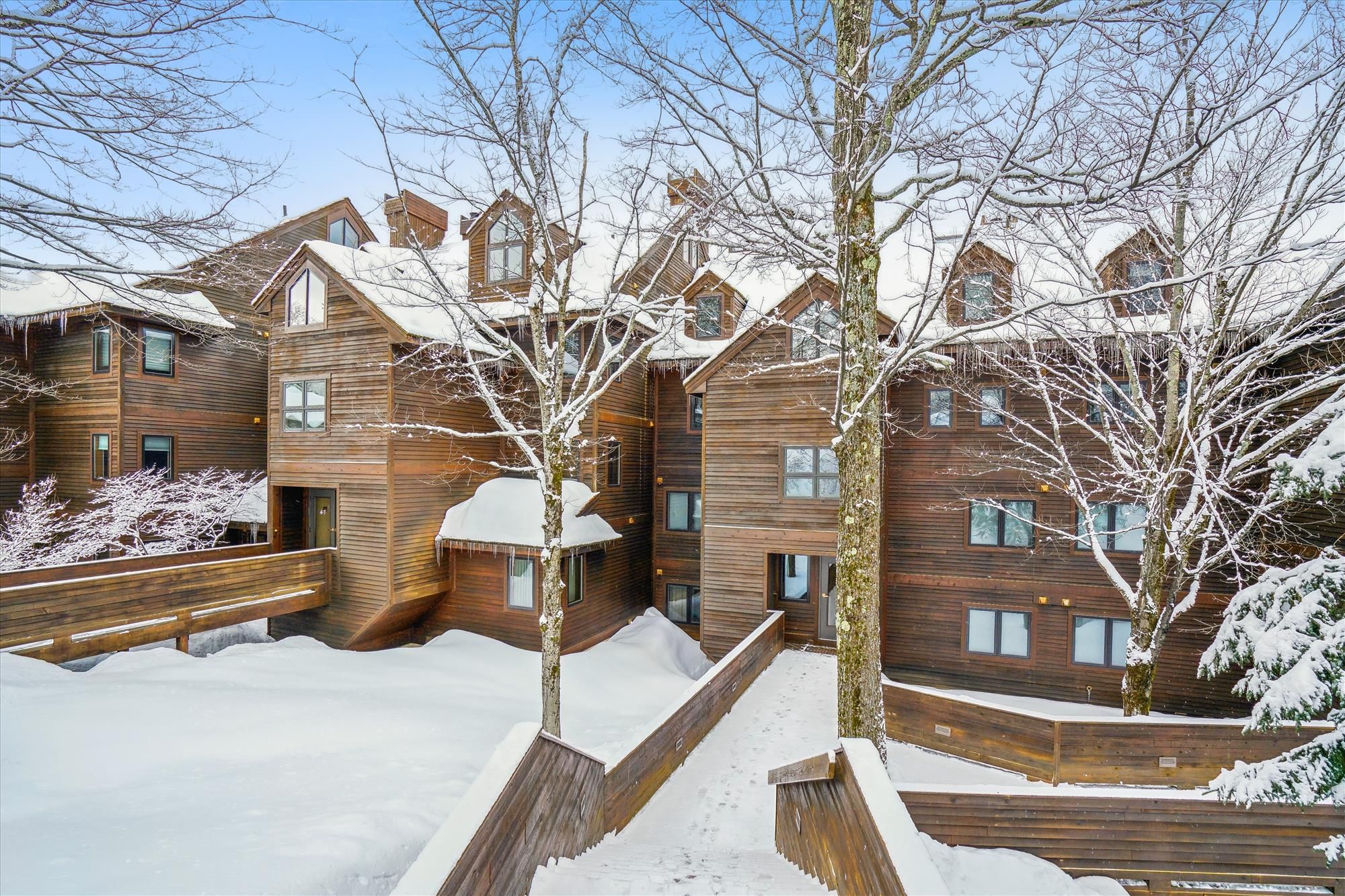 A multi-story wooden building with a snow-covered landscape, wooden railings, and a clear sky.